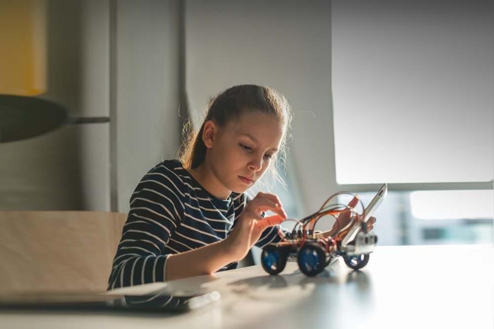 Young female student in a striped shirt working on the electronic toy enjoying his STEM class at Georgia Connections Academy